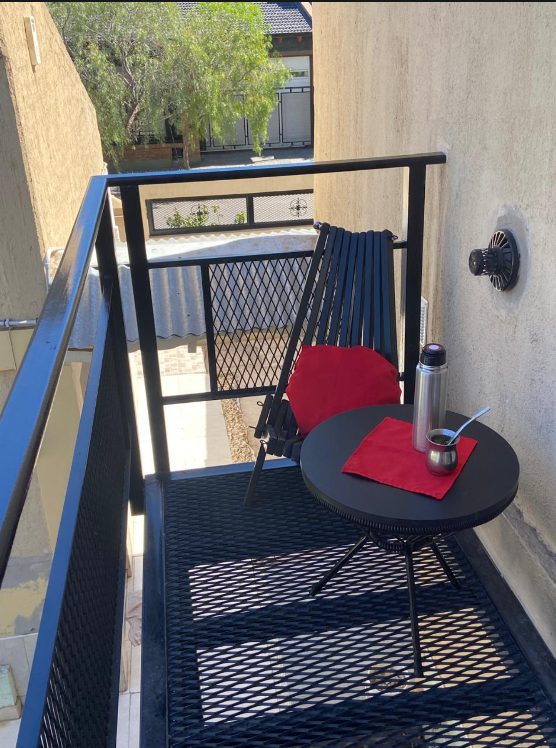 Balcón de Murmullos de Sueño con mesa, silla y termo, listo para tomar mate al aire libre